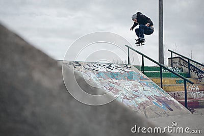 Skateboarder doing a Ollie over the rail in a skatepark Stock Photo