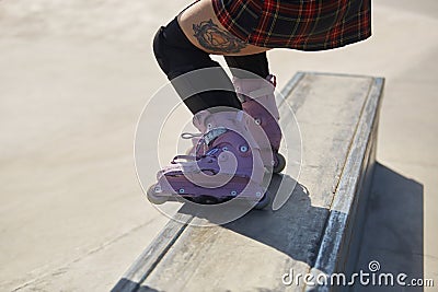 Skater girl grinding on a ledge in a skatepark. Feet of aggressive inline roller blader performing a bs full torque grind in close Stock Photo