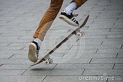 Skater legs wearing black sneakers by Adidas jumping with skate board in the street Editorial Stock Photo