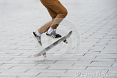 Skater legs wearing black sneakers by Adidas jumping with skate board in the street Editorial Stock Photo