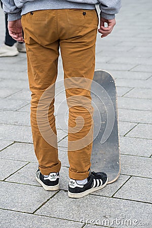 Skater legs wearing black sneakers by Adidas standing with skate board in the street Editorial Stock Photo