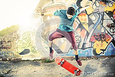 Skater in movement making a trick with his skate at sunset Stock Photo