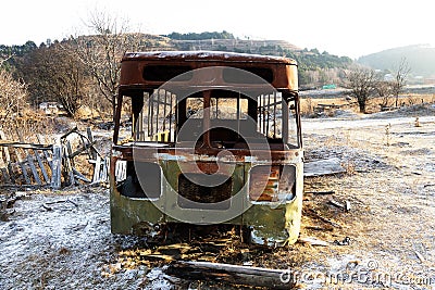 skeleton of abandoned old bus against winter hills Stock Photo