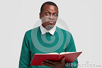 Skeptical confused dark skinned unshaven man has surprised facial expression in bewilderment, reads something from Stock Photo