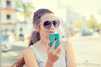 Skeptical, doubtful shocked anxious scared young girl looking at phone Stock Photo