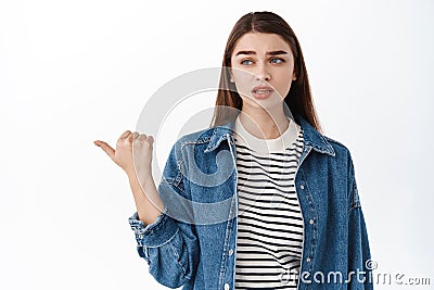Skeptical, doubtful young woman looking and pointing aside at left copyspace with suspicious, unsure face, having doubts Stock Photo