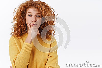 Skeptical, judgemental redhead woman with curly hair, rub chin and squinting as looking camera, give-out her opinion Stock Photo