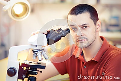 Skeptical Young Male Researcher with microscope Stock Photo