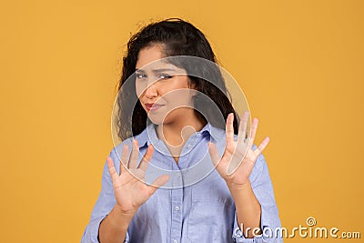 Skeptical young woman in a blue shirt, showing her palms in a defensive stop Stock Photo