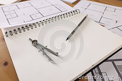 Sketchbook with construction drawings, pair of compasses and pencil on wooden table, closeup Stock Photo