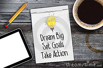 Sketchbook with Dream big, set goals, take action on a wooden desk with coffee, pen and tablet Stock Photo