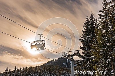 Four skiers on a chair lift against the backdrop of the sun and trees, contour photo, orange shades, ski region Schladming Austria Editorial Stock Photo