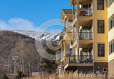 Ski condos with forest and snowy mountain in the background against blue sky on a sunny day Stock Photo