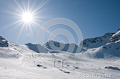 Ski lift at high altitude resort, sun with flare Stock Photo