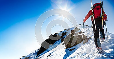 Ski mountaineer walking up along a steep snowy ridge with the sk Stock Photo