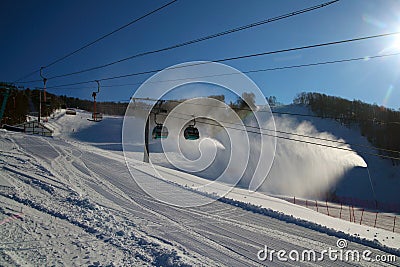 Ski piste and gondola lift and snow guns operating Stock Photo