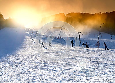 Ski resort, snowmaking on artificial slopes at sunset. Stock Photo