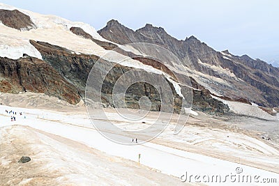 Ski slope with skiers at mountain Allalinhorn and snow mountain panorama during summer near Saas-Fee in Pennine Alps, Switzerland Stock Photo