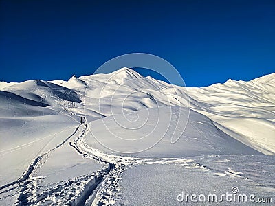 Ski touring track with snowy mountain peaks in the background, Skimo mountaineering in St. Antonien near Davos Stock Photo