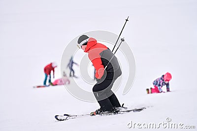 A skier goes down a snow-covered slope. In the background, blurry images of snowboarders. Selective focus Stock Photo