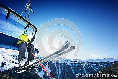 Skier siting on ski-lift - lift at sunny day and mountain Stock Photo