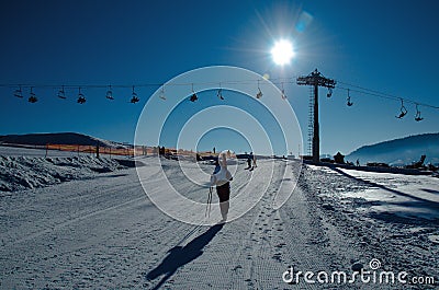 A skier with skis on his shoulder walks along the road to the ski lift Editorial Stock Photo