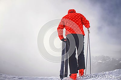 Skier stay with skis on mountain edge above deep slope valley Stock Photo