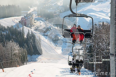 Skiers on cable car in Bukovel with background snow-covered slopes Stock Photo