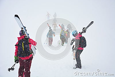 Skiers carries skis and equipments to the track on a slope for skiing on Mount Asahi Asahidake mountain during snowfall Editorial Stock Photo