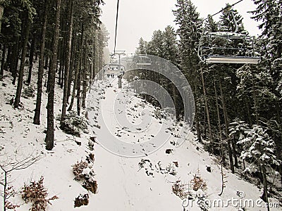 Skiers climb up the slope by cable car in the snow-covered forest Stock Photo