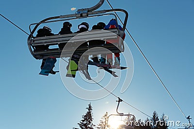 Skiers and snowboarders on ski lift against blue sky in the mountain at winter vacation Editorial Stock Photo