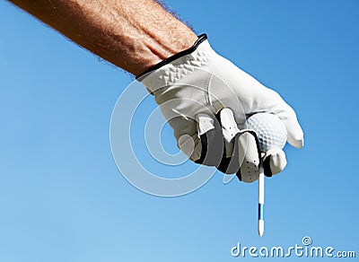 The skies the limit if you practice hard enough. A golfers hand holding his tee and golfball against a blue sky. Stock Photo