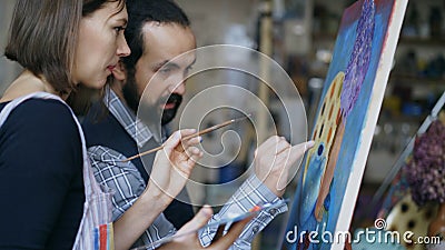 Skilled artist teacher showing and discussing basics of painting to student at art-class Stock Photo