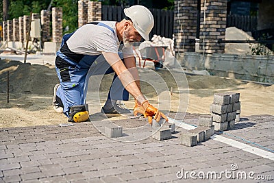 Skilled builder paving road on construction site Stock Photo