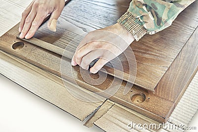 Skilled carpenter assembles wooden door fixing glazing bead Stock Photo