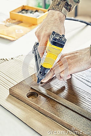 Skilled carpenter assembles wooden door fixing glazing bead Stock Photo