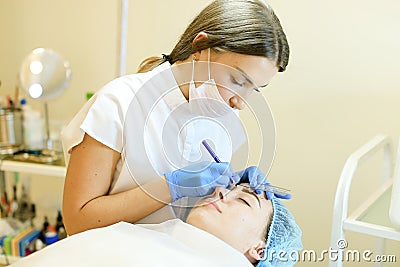 Skilled cosmetologist shaping eyebrows for young girl before microblading. Stock Photo