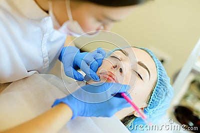 Skilled cosmetologist shaping lips with pencil for pretty girl before microblading. Stock Photo