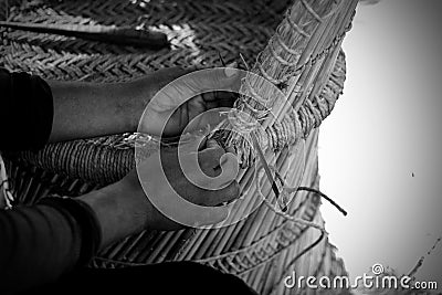 Skilled craftsman working manually a detailed bamboo wood armchair with his fingers and tools Stock Photo