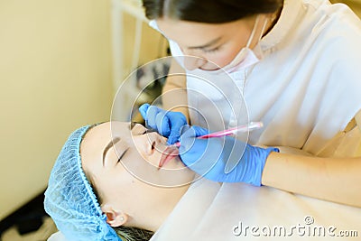 Skilled female cosmetologist shaping lips with pencil for young girl before microblading. Stock Photo