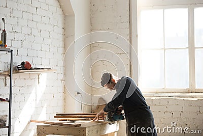 Professional carpenter using power hand saw in workshop, side vi Stock Photo