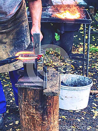 Skilled smith man striking a red hot horseshoe on the anvil Stock Photo