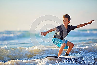 Skilled teenager riding surfboard and balancing a long wavy sea. Stock Photo