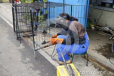 A skilled worker weld iron bars together to form a dog cage Editorial Stock Photo