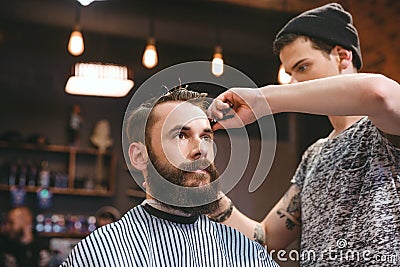 Skillful barber cutting hair of young man with beard Stock Photo