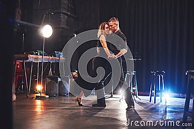 Skillful dancers performing in the dark room under the light Stock Photo