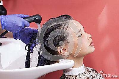 Skillful hairdresser washes hair before styling, long haired teen girl in hair salon Stock Photo