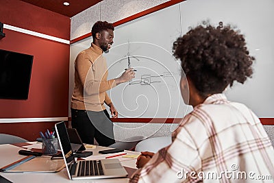 Skillful male designer drawing while standing in front of the white board Stock Photo