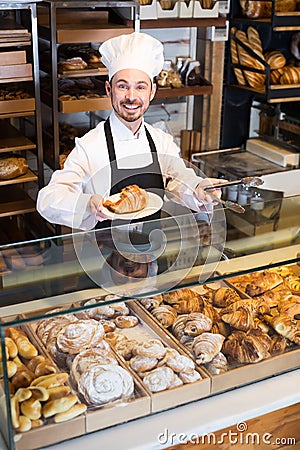 Skillful male pastry maker demonstrating croissant Stock Photo