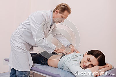 Skillful specialist helping young lady get rid of pain Stock Photo